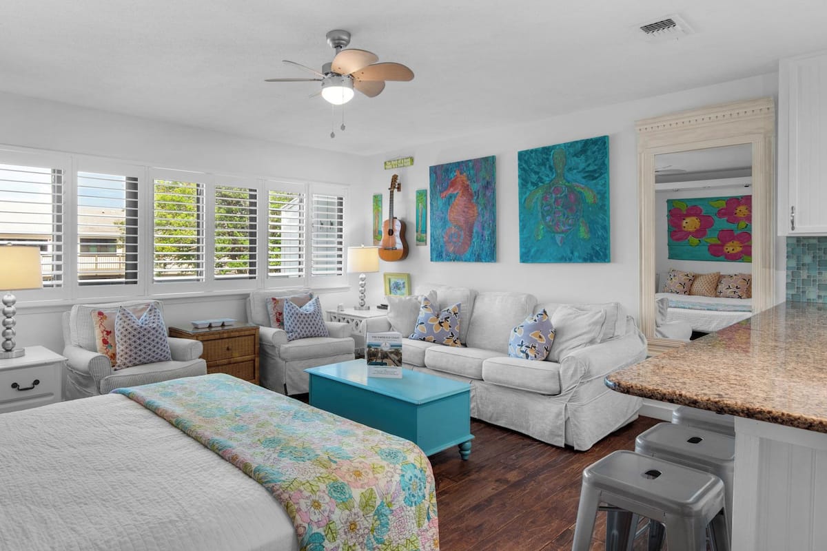 A bedroom with a bed, a sofa, a coffee table, and a ceiling fan.