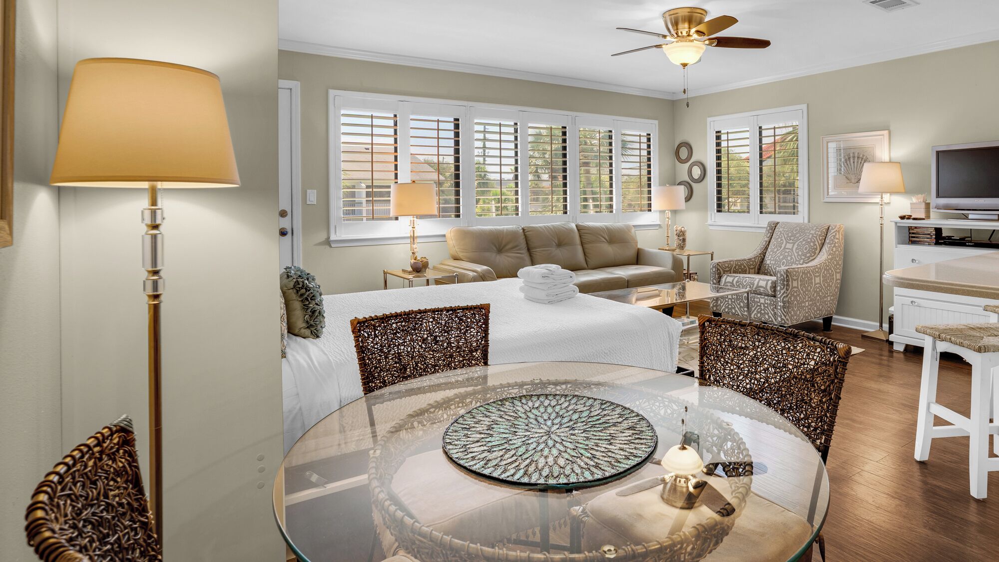 A spacious living room with a round glass table, a sofa, a chair, and a television.