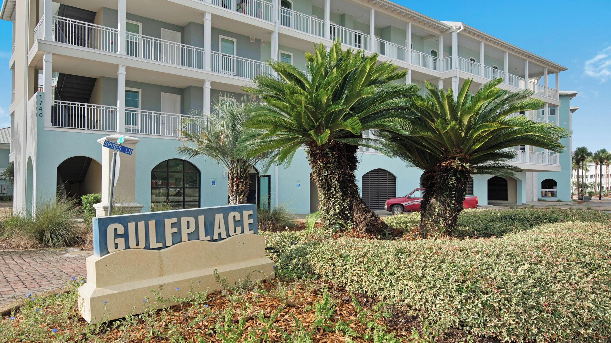 A multi-story hotel with a light blue facade, palm trees, and a sign reading "GULFPLACE".