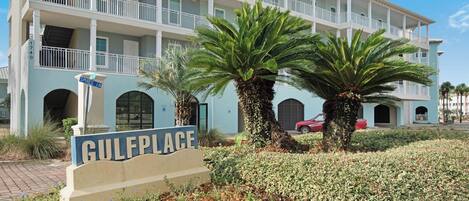 A multi-story hotel with a light blue facade, palm trees, and a sign reading "GULFPLACE".
