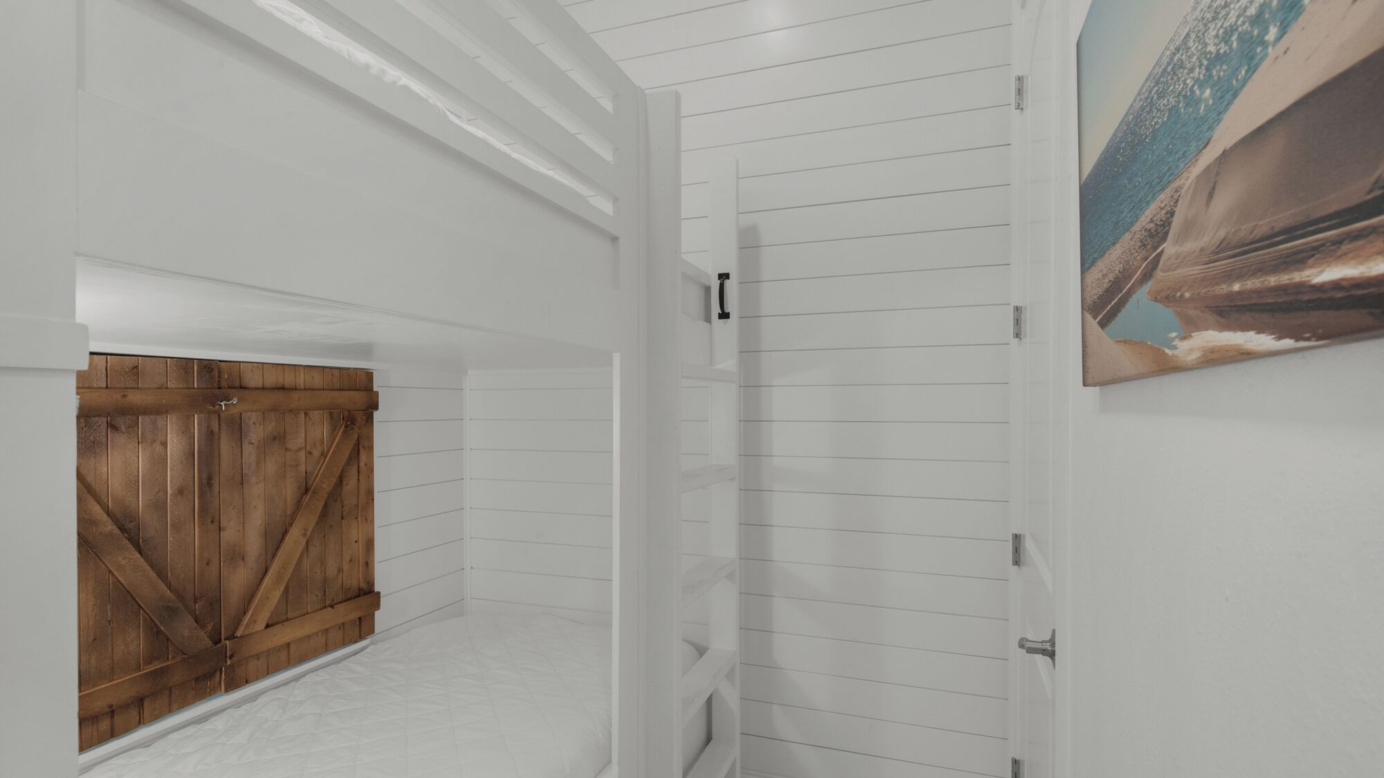A hallway with white paneling, a wooden door, and a painting on the wall.