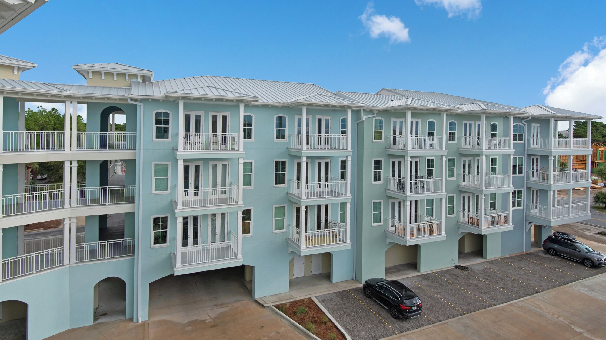Un immeuble à plusieurs étages doté de balcons, d’un espace de stationnement et surplombant un ciel dégagé.
