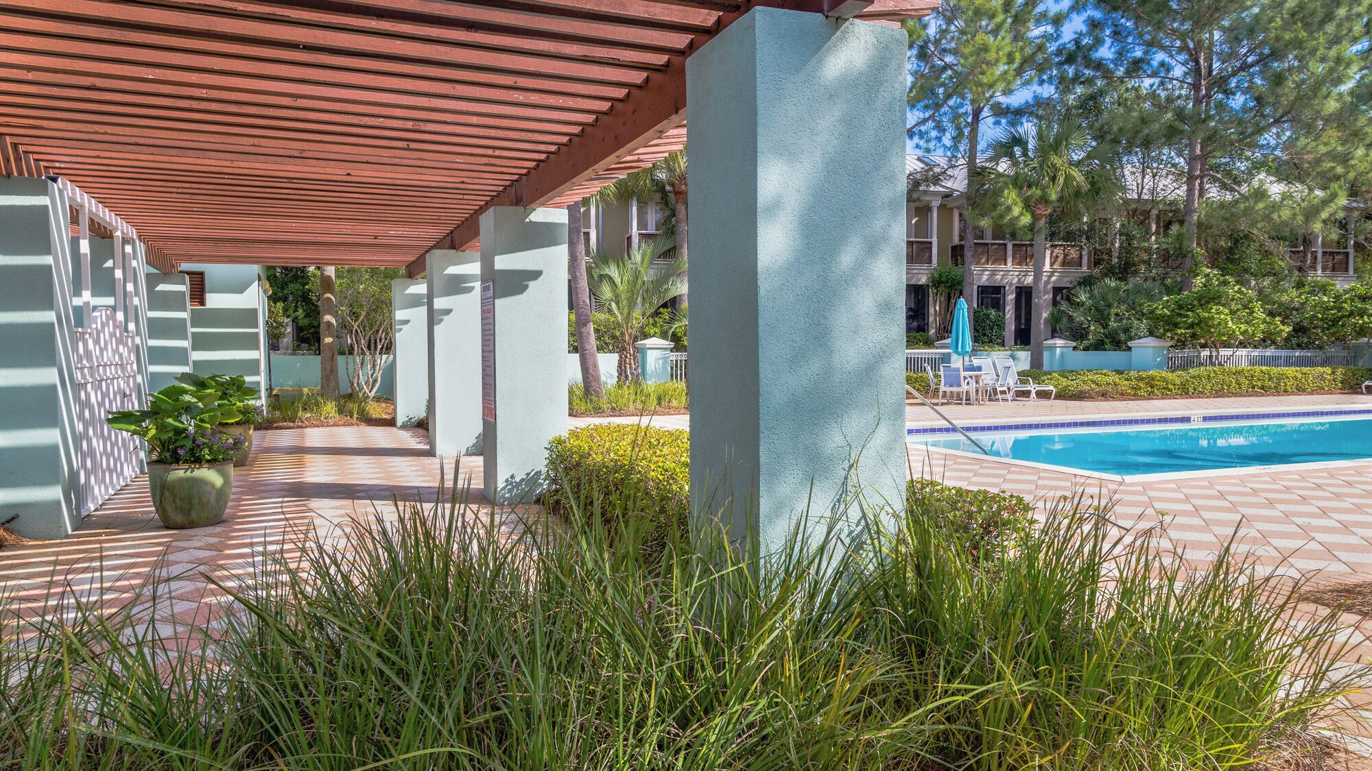 A pool area with a covered walkway, potted plants, and a clear view of the pool.