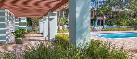 A pool area with a covered walkway, potted plants, and a clear view of the pool.