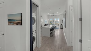 Una cocina moderna con una isla central, un comedor con taburetes de bar y vistas al océano a través de un ventanal grande.