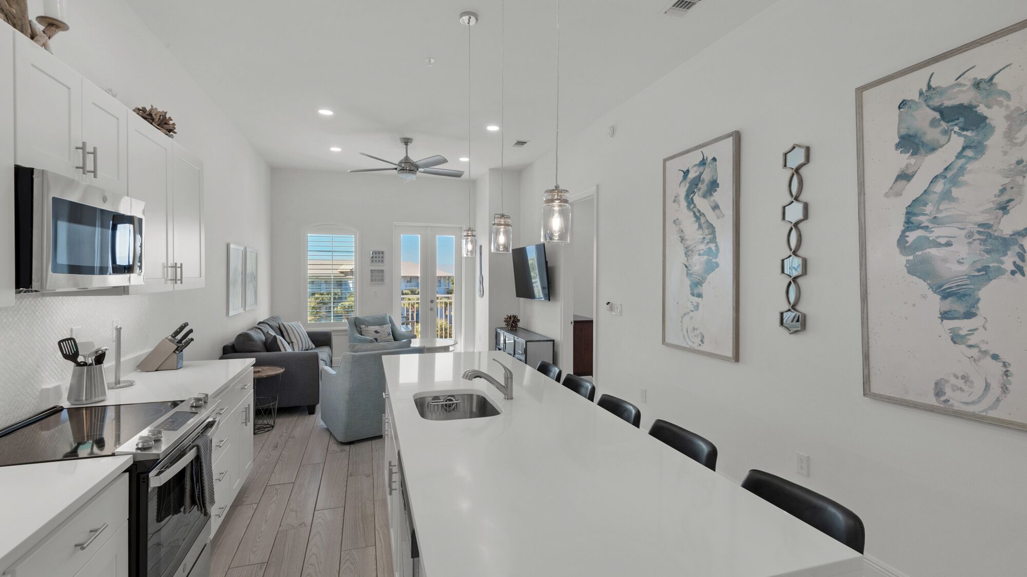 A modern kitchen with a central island, white cabinetry, and a dining area with chairs.