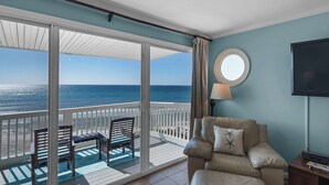 Een balkon met uitzicht op de oceaan, een stoel, een tafel en een lamp.