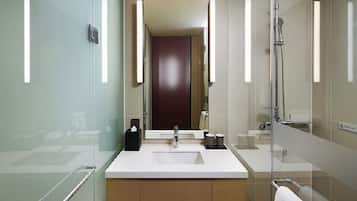 A modern bathroom with a glass shower enclosure, a large mirror, a white sink, and a towel rack.