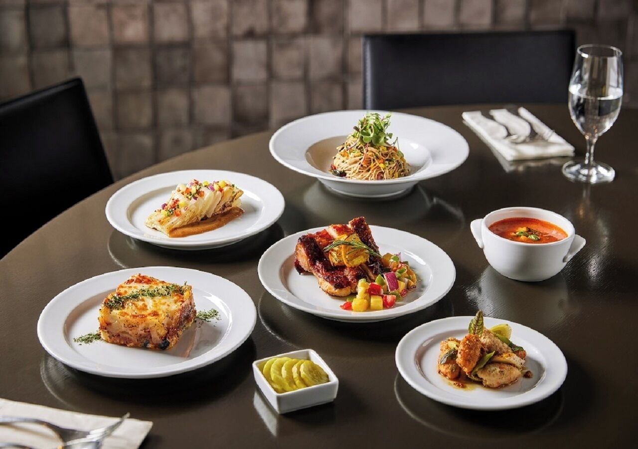 A dining table with various dishes, including a piece of lasagna, a salad, and a bowl of soup.