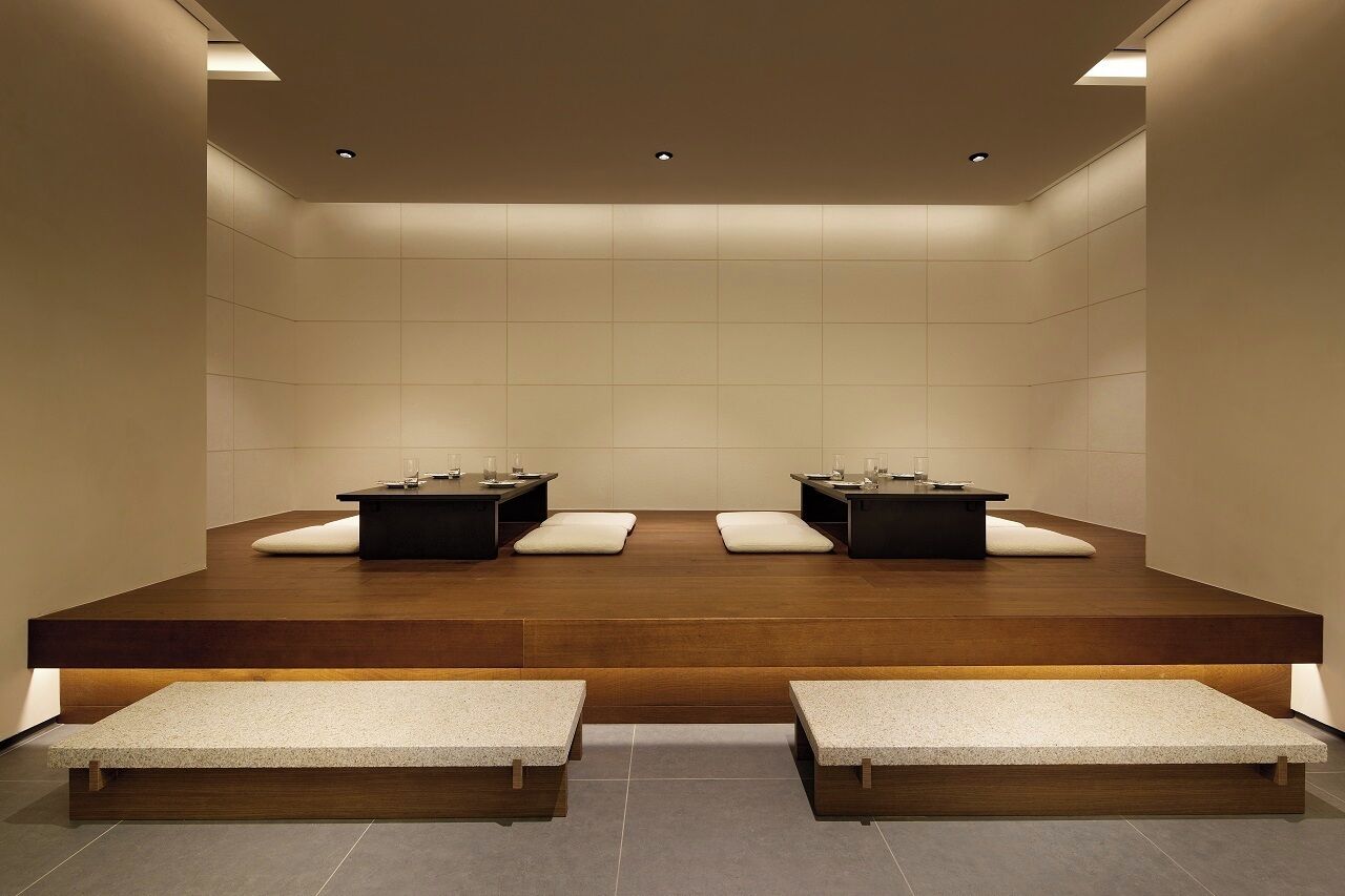 Un'area spa moderna e minimalista con due lettini da massaggio, panche e una piattaforma in legno.
