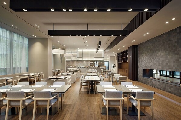 A modern dining area with multiple tables and chairs, a kitchen in the background, and a large flat-screen TV mounted on the wall. - Shilla Stay Jeonju Hanok Village (Jeonju)