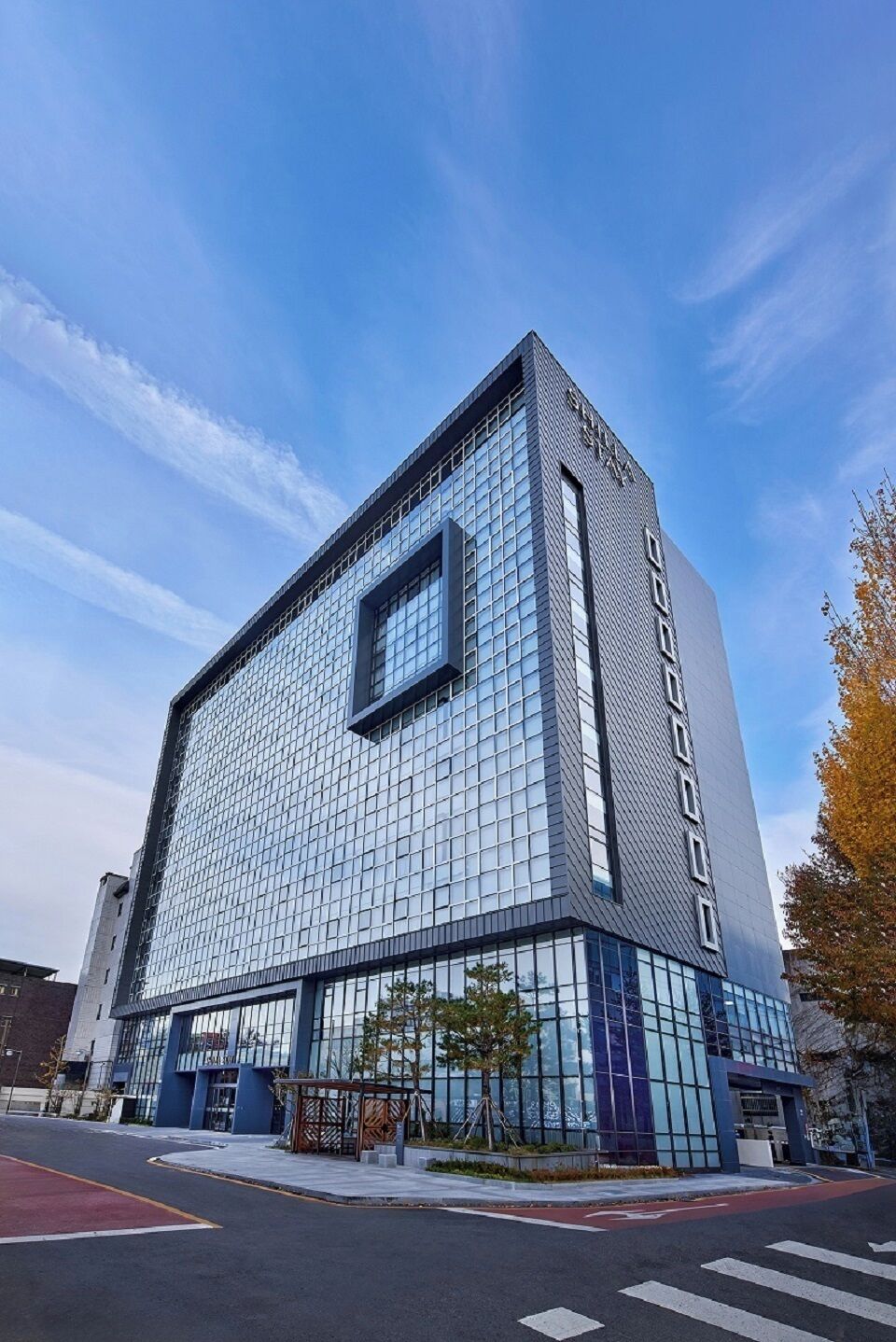 Un bâtiment moderne doté d’une façade en verre, d’une entrée imposante et surplombant un ciel dégagé.