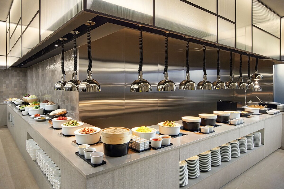 A modern kitchen with stainless steel appliances, a variety of food dishes, and neatly arranged plates and bowls.