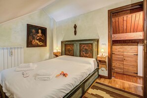 A bedroom with a large bed, a wooden headboard, a painting on the wall, and a wooden wardrobe. - Grangia Sunset View (Sauze di Cesana)
