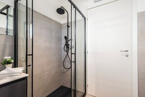 A modern bathroom with a glass shower enclosure, a white sink with a towel, and a potted plant. - Always Traveling Near The City Center (Olbia)