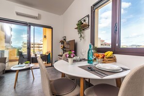 A dining area with a round table, chairs, and a view through a glass door to the outside. - Always Traveling Near The City Center (Olbia)