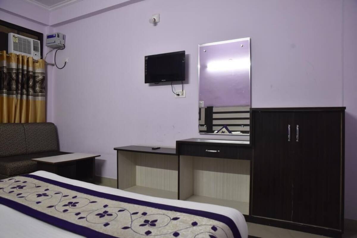A hotel room with a bed, a desk, a television, and a wardrobe.