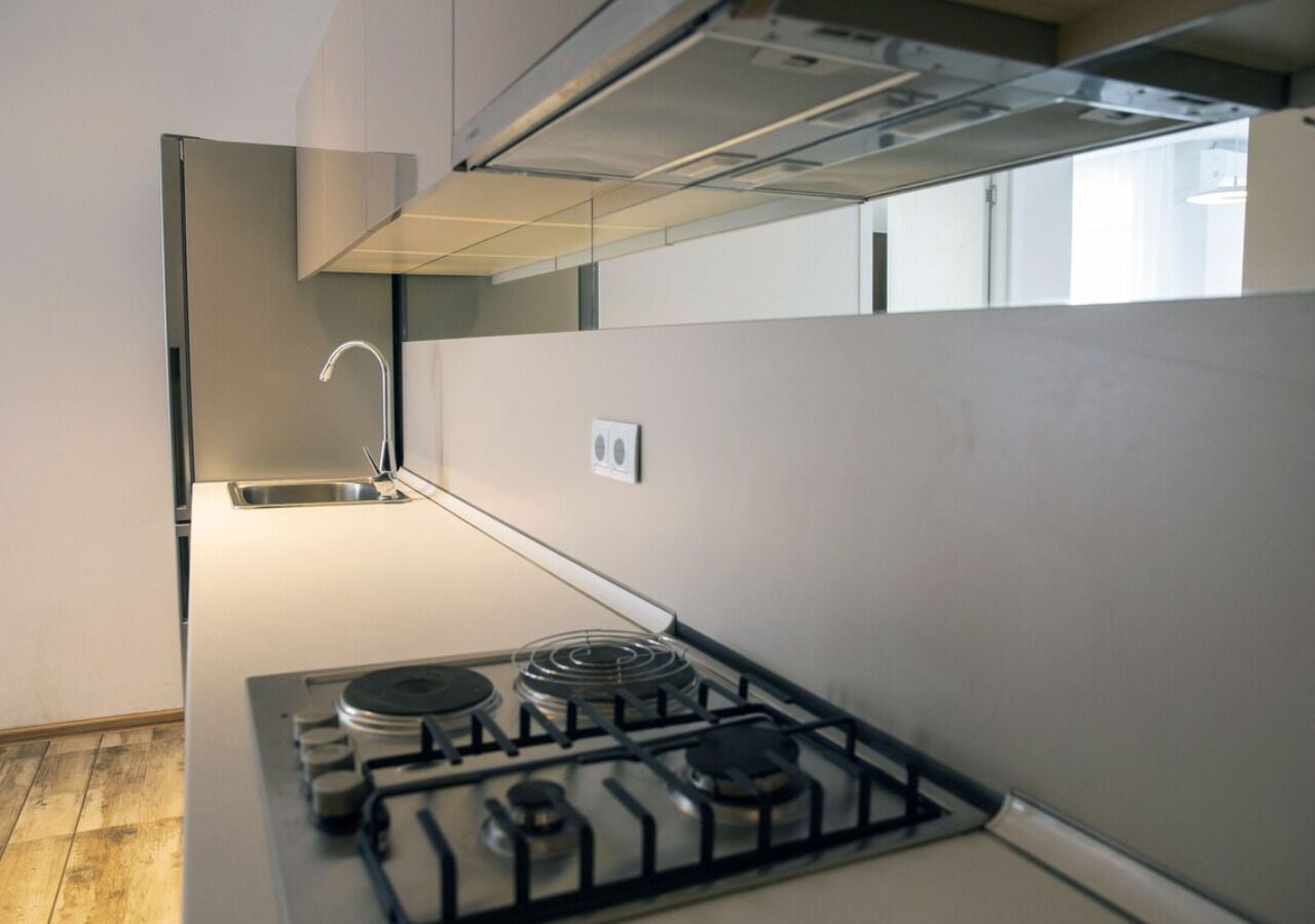 A modern kitchen with a gas stove, a stainless steel sink, and a range hood.