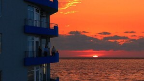 A building with multiple balconies overlooking a sunset over the ocean. - Horizon Batumi Aparthotel (Batumi)