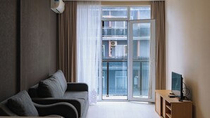 A modern living room with a sofa, a dining table, and a TV stand. - Horizon Batumi Aparthotel (Batumi)