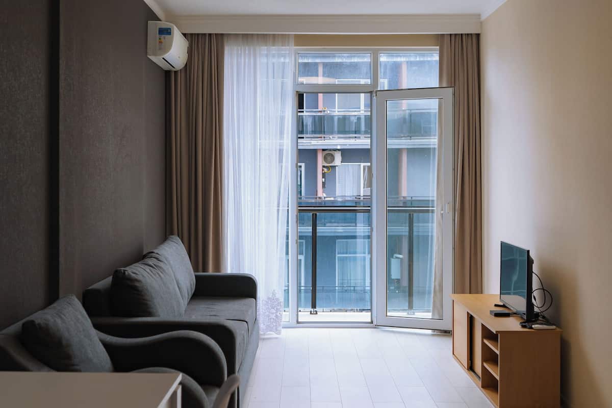 Ein modernes Wohnzimmer mit einer Couch, einem Esstisch und einer TV-Konsole.