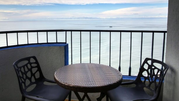 A balcony with a round table and two chairs, overlooking a calm sea. - Horizon Batumi Aparthotel (Batumi)