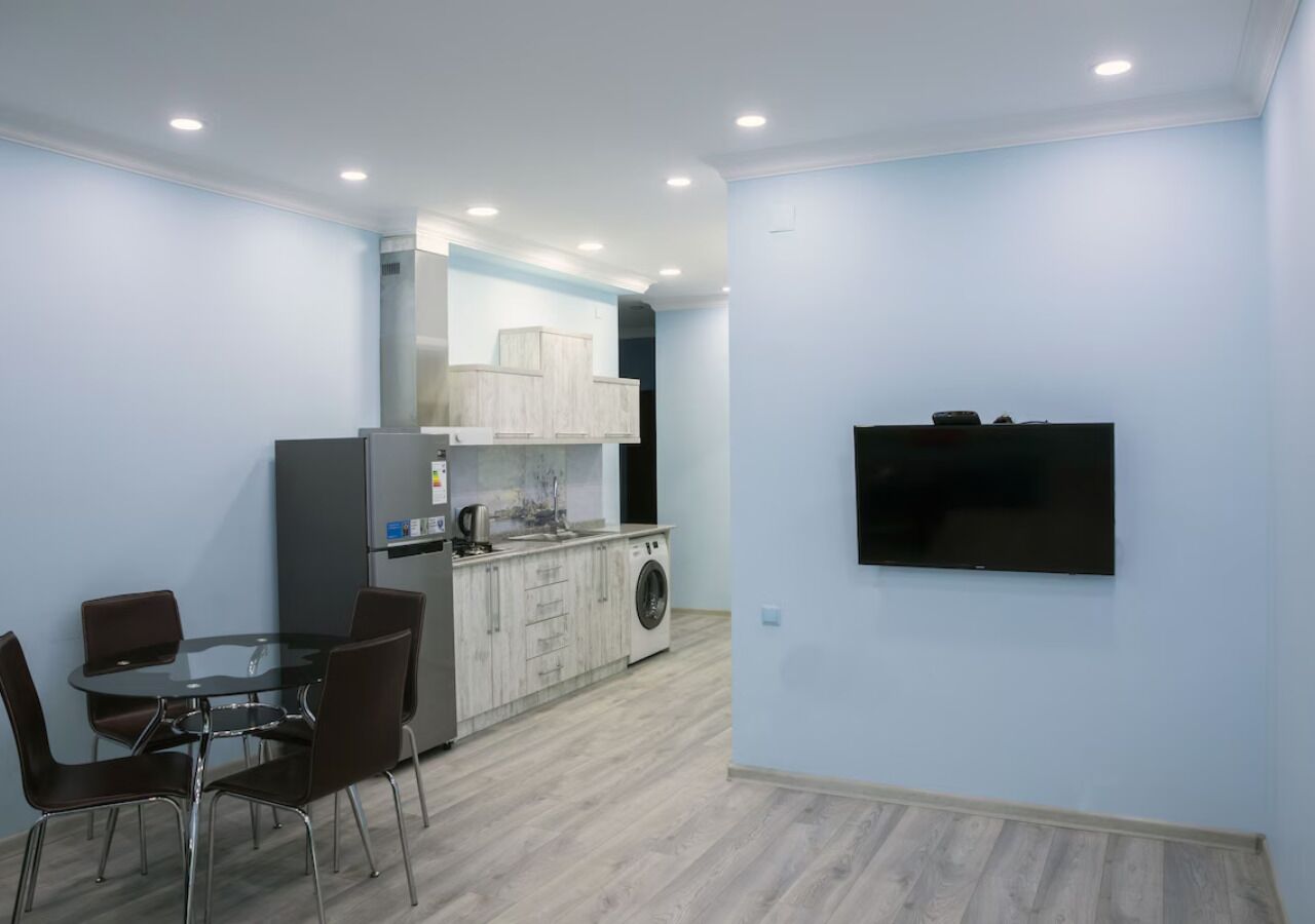 A modern kitchen with a dining area, built-in appliances, and a flat-screen TV.