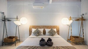 A neatly arranged bedroom with a large bed, two wall-mounted lamps, and a ceiling fan. - Villa Dolcevita Seminyak  (Seminyak)