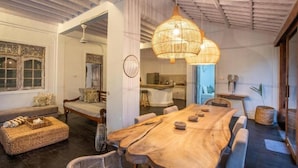 A spacious dining area with a large wooden table, wicker furniture, and a hanging rattan light fixture. - Villa Dolcevita Seminyak  (Seminyak)