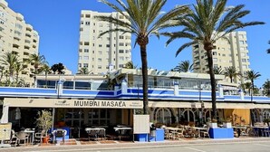 Un restaurante llamado 'Mumbai Masala' con terraza y palmeras al frente.