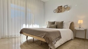 Un dormitorio con cama, mesita de noche, lámpara y un adorno en la pared.