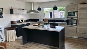 Cocina moderna con una isla central, electrodomésticos integrados y vistas al exterior.