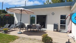 Un patio con mobiliario exterior, una mesa y una sombrilla grande.