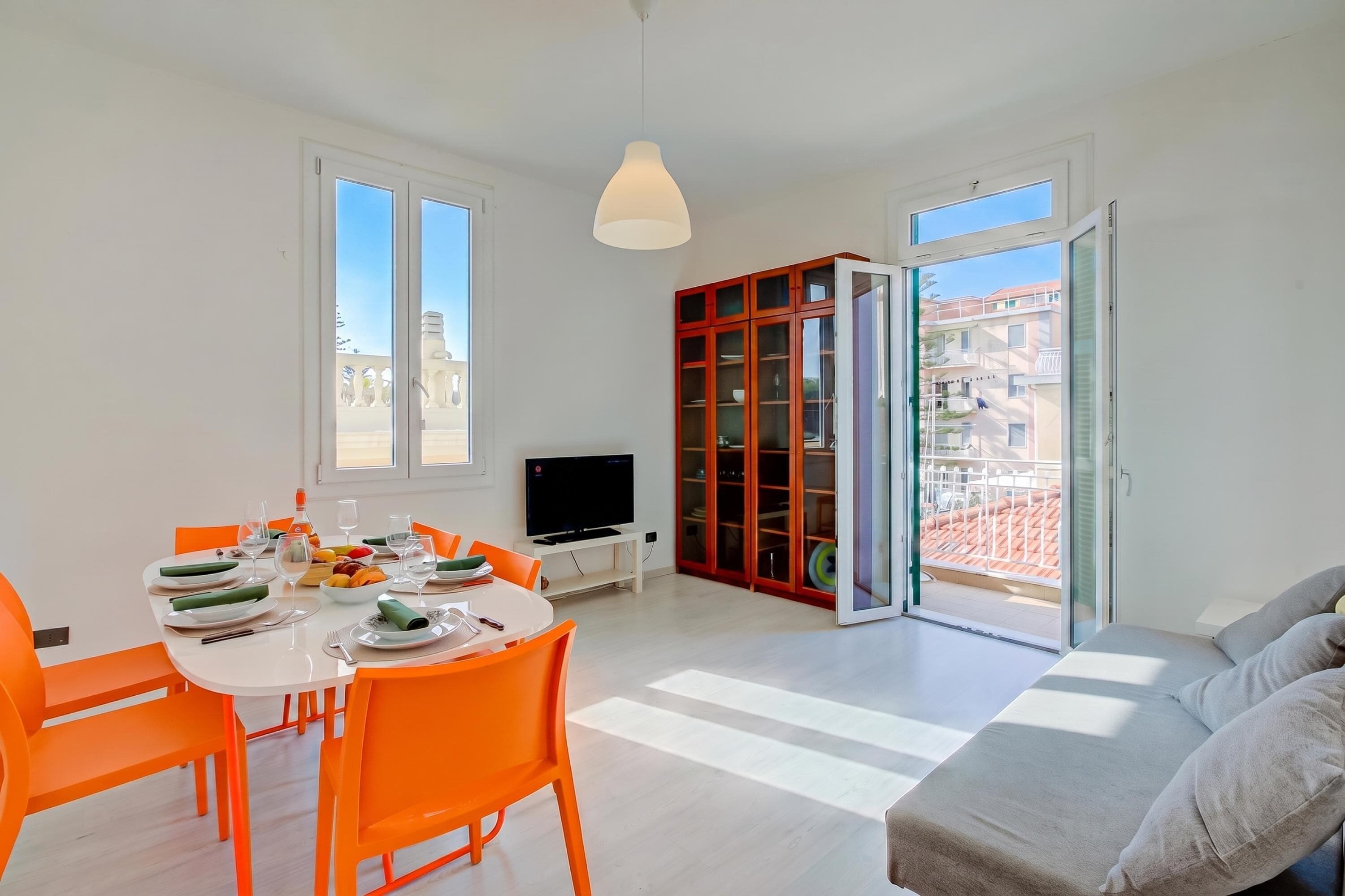 A modern living room with a dining area, a television, and a red cabinet.