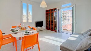 A modern living room with a dining area, a television, and a red cabinet. - Serendipity Spiaggia E Porto Sole With Balcony and Parking (Sanremo)