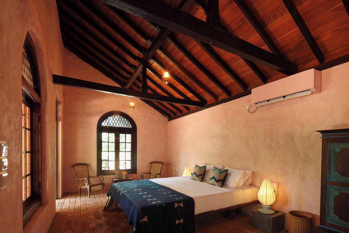 Une chambre à coucher avec un lit, une chaise, une lampe et une fenêtre.