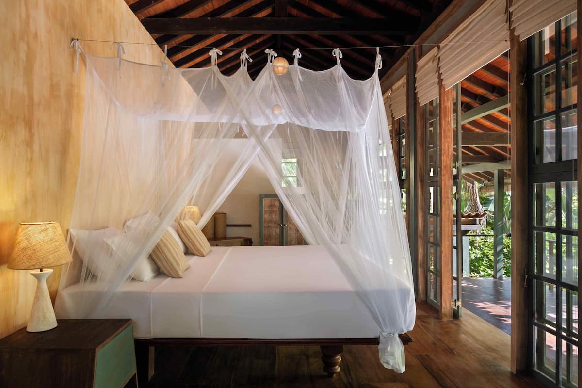 Une chambre à coucher avec un lit à baldaquin, un plancher en bois et de grandes fenêtres.