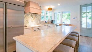 A modern kitchen with a large island, stainless steel appliances, and a herringbone backsplash. - Community Pool, 7 Minute Walk to Beach & Golf Views! Fully Renovated, Single Story Beach Bungalow! (Isle of Palms)
