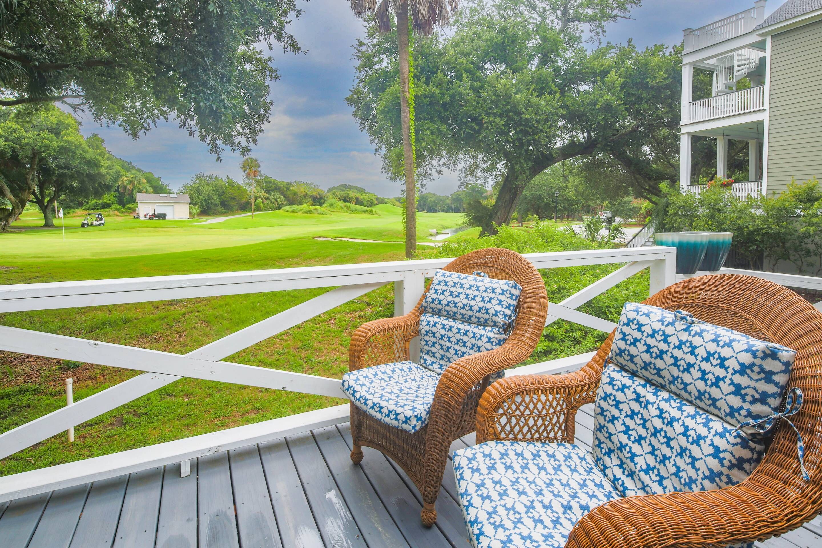 A deck with wicker chairs and a view of a golf course.