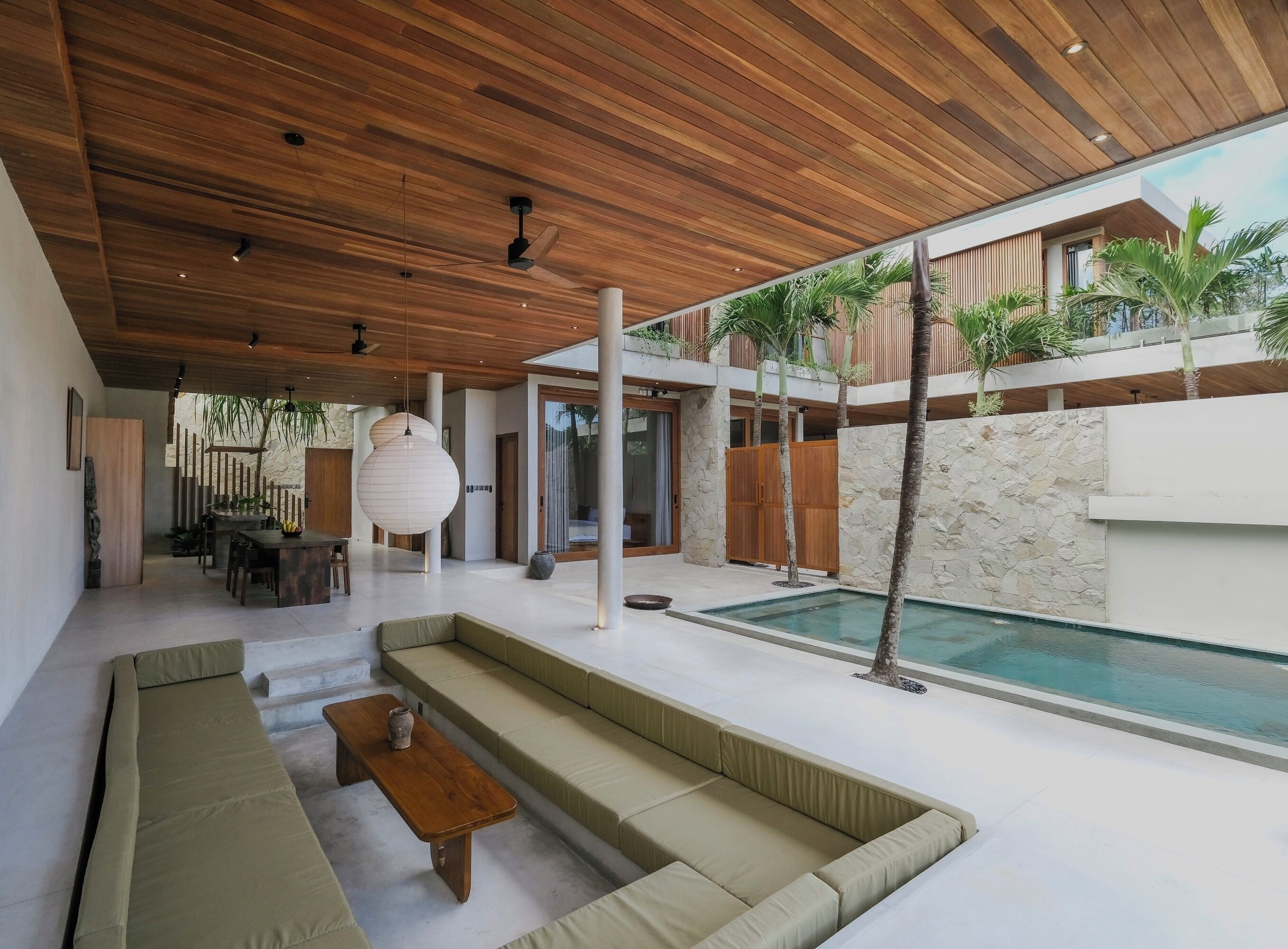 Un espacio exterior moderno con piscina, techo de madera y mobiliario.