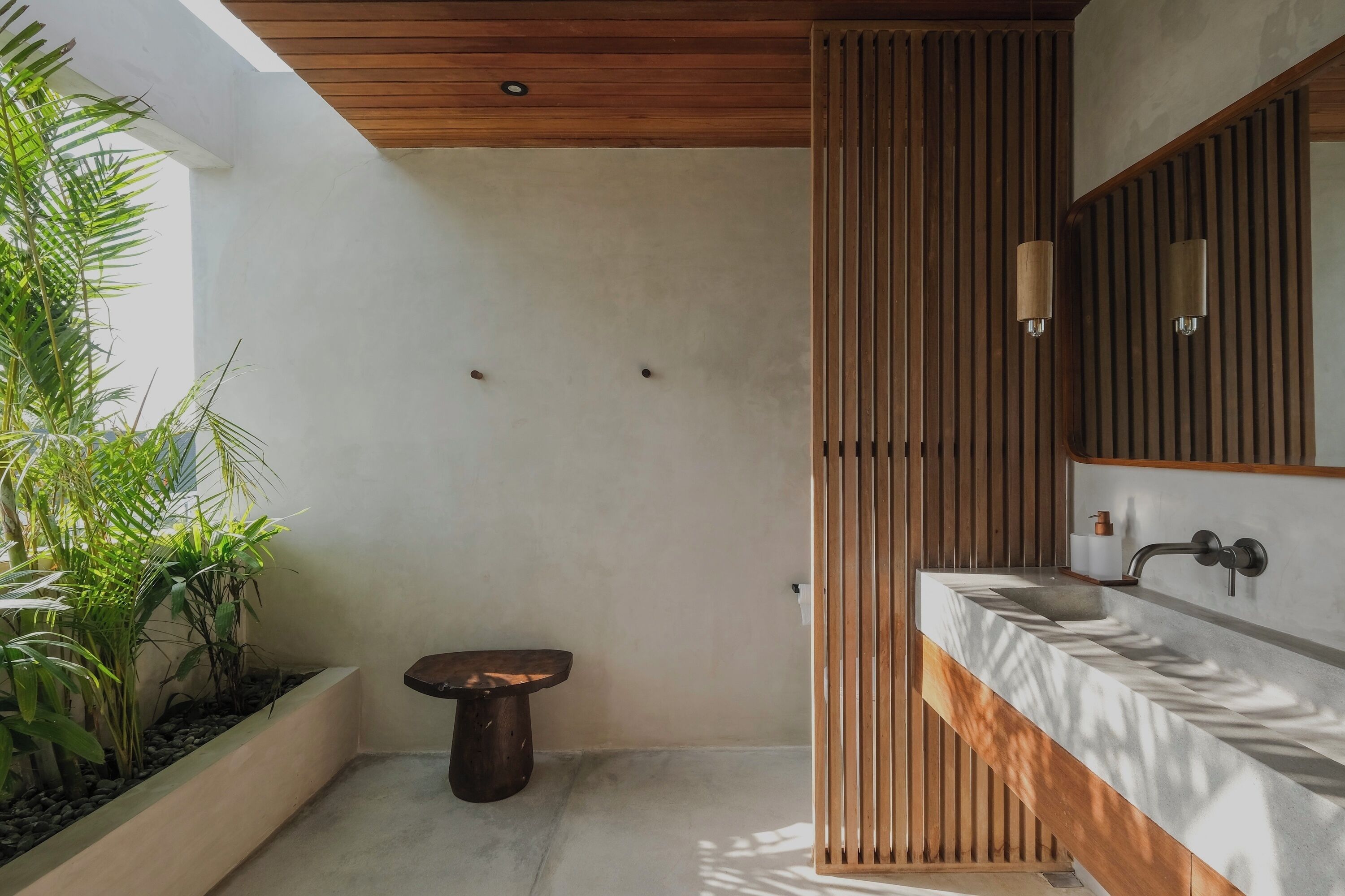 A modern bathroom with a wooden ceiling, a large mirror, and a built-in sink.