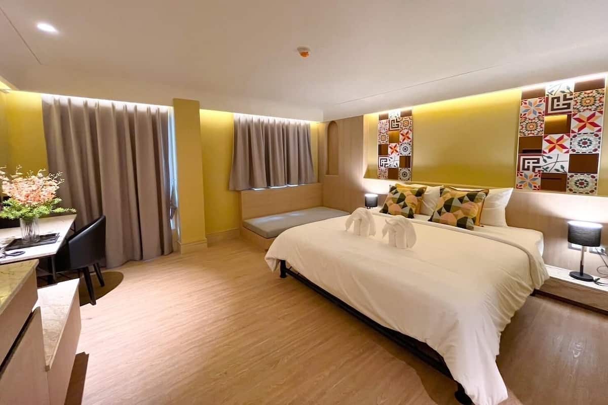 Une chambre d’hôtel moderne équipée d’un lit, de tables de chevet, d’un bureau et d’une chaise.