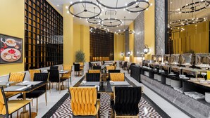 Ein Restaurant mit einer langen Theke, schwarzen und gelben Stühlen sowie einem gemusterten Boden.