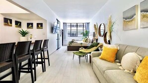 A modern living room with a sofa, chairs, a dining area, and artwork on the walls. - Beautiful Retreat w. Pool and Perfect Location (San Juan)