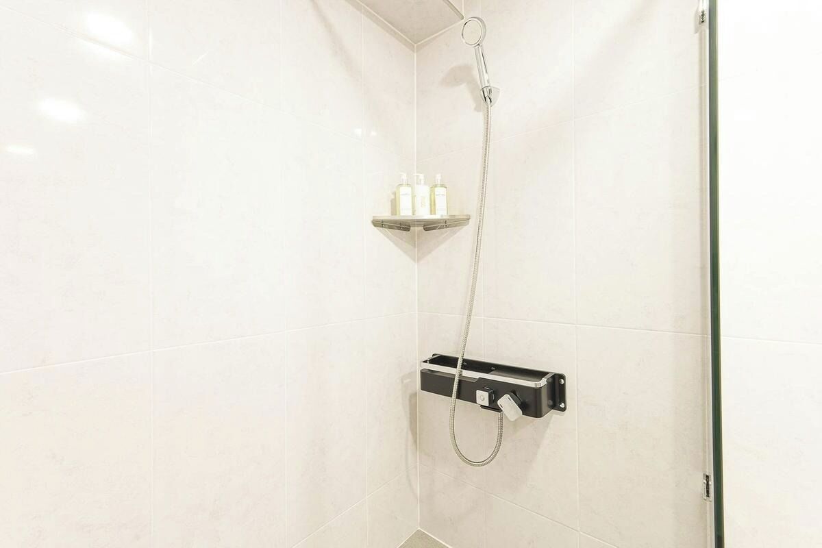 A shower area with a handheld showerhead, a soap dish, and a towel rack.