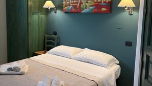 Ein Hotelzimmer mit einem Bett, zwei Wandlampen, einem Gemälde und einem grünen Kleiderschrank.