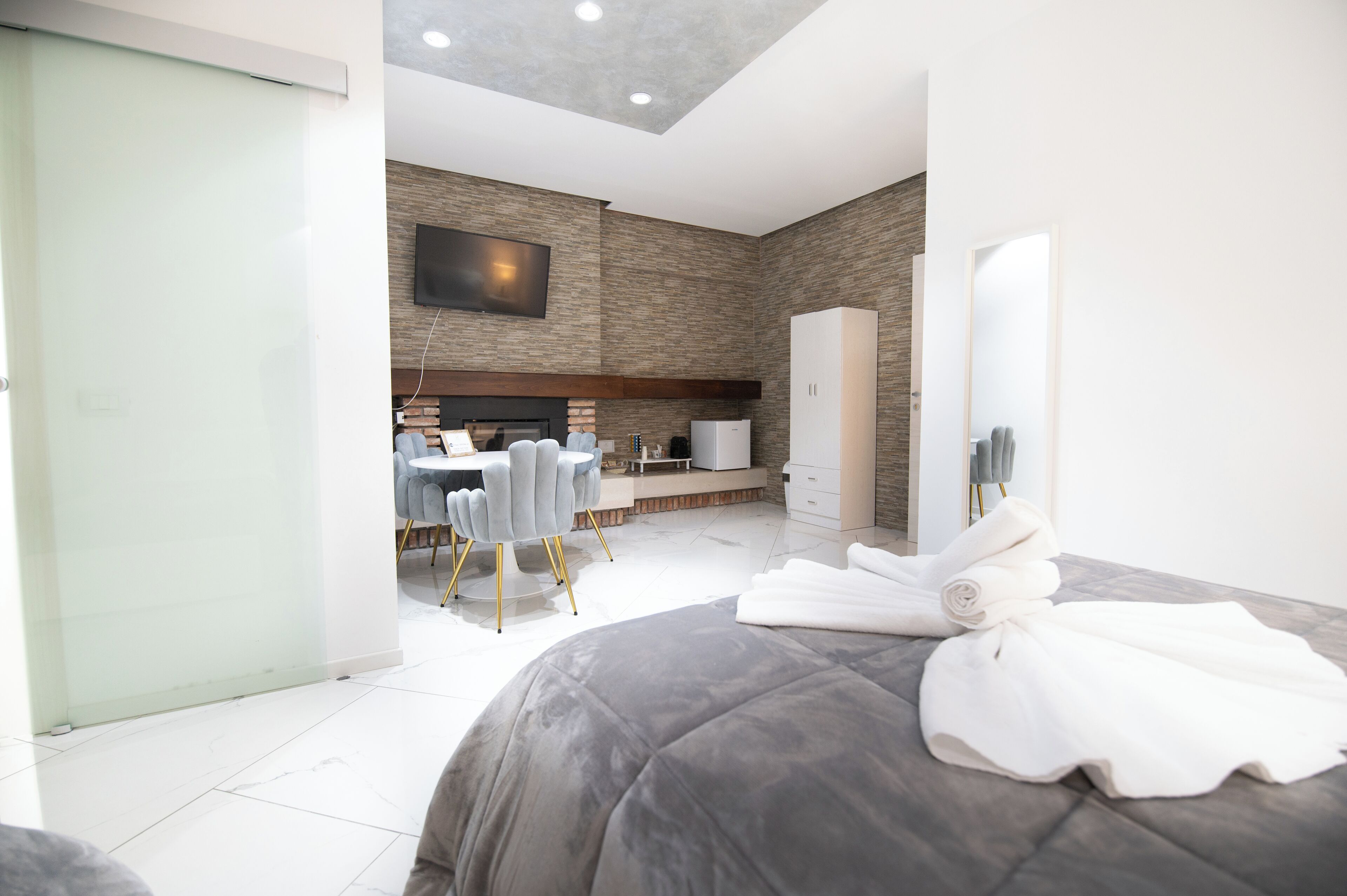 Een moderne hotelkamer met een groot bed, een zithoek met een ronde tafel en stoelen, een flatscreen televisie aan de muur en een kledingkast.