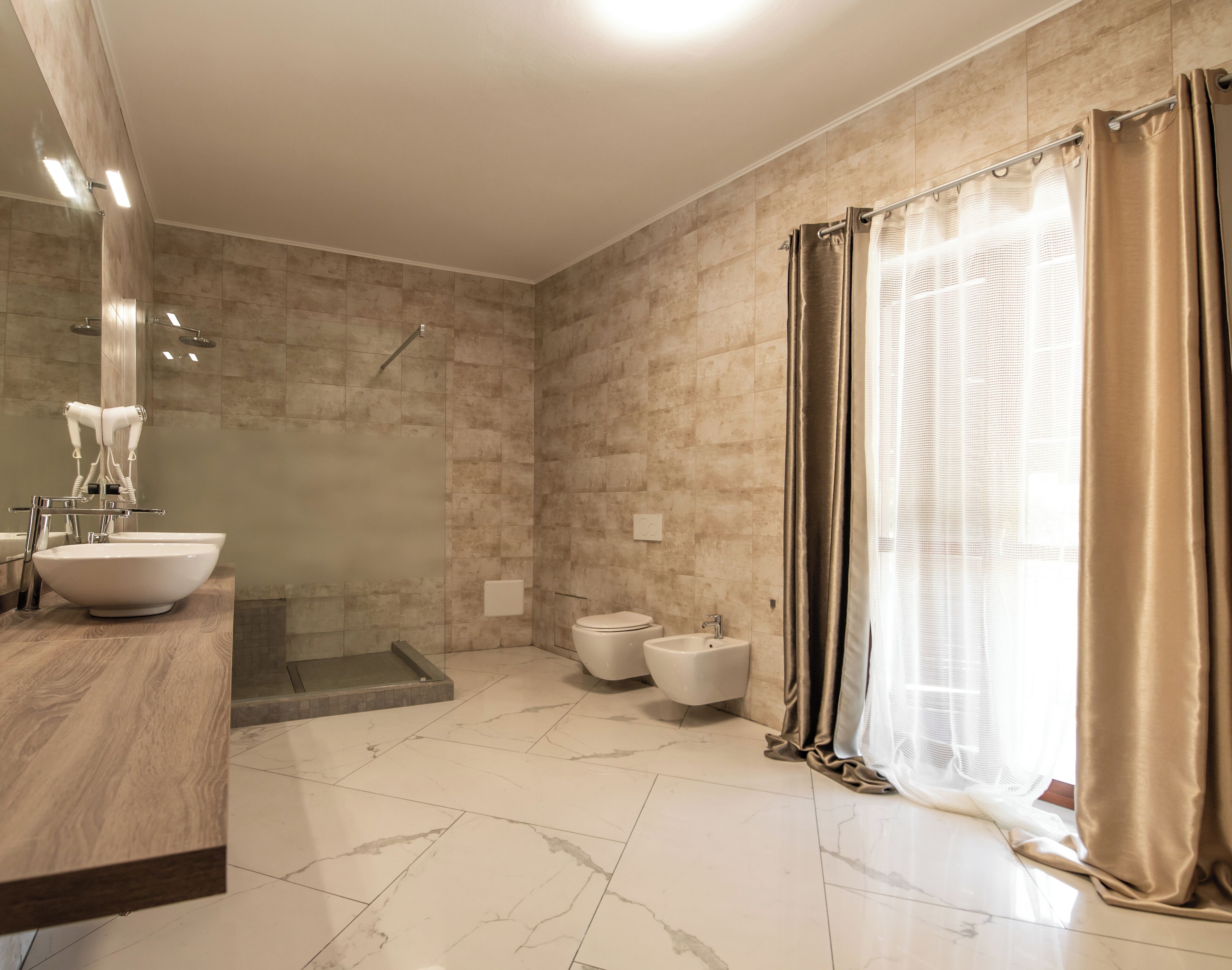 A modern bathroom with a large sink, a walk-in shower, and a toilet.