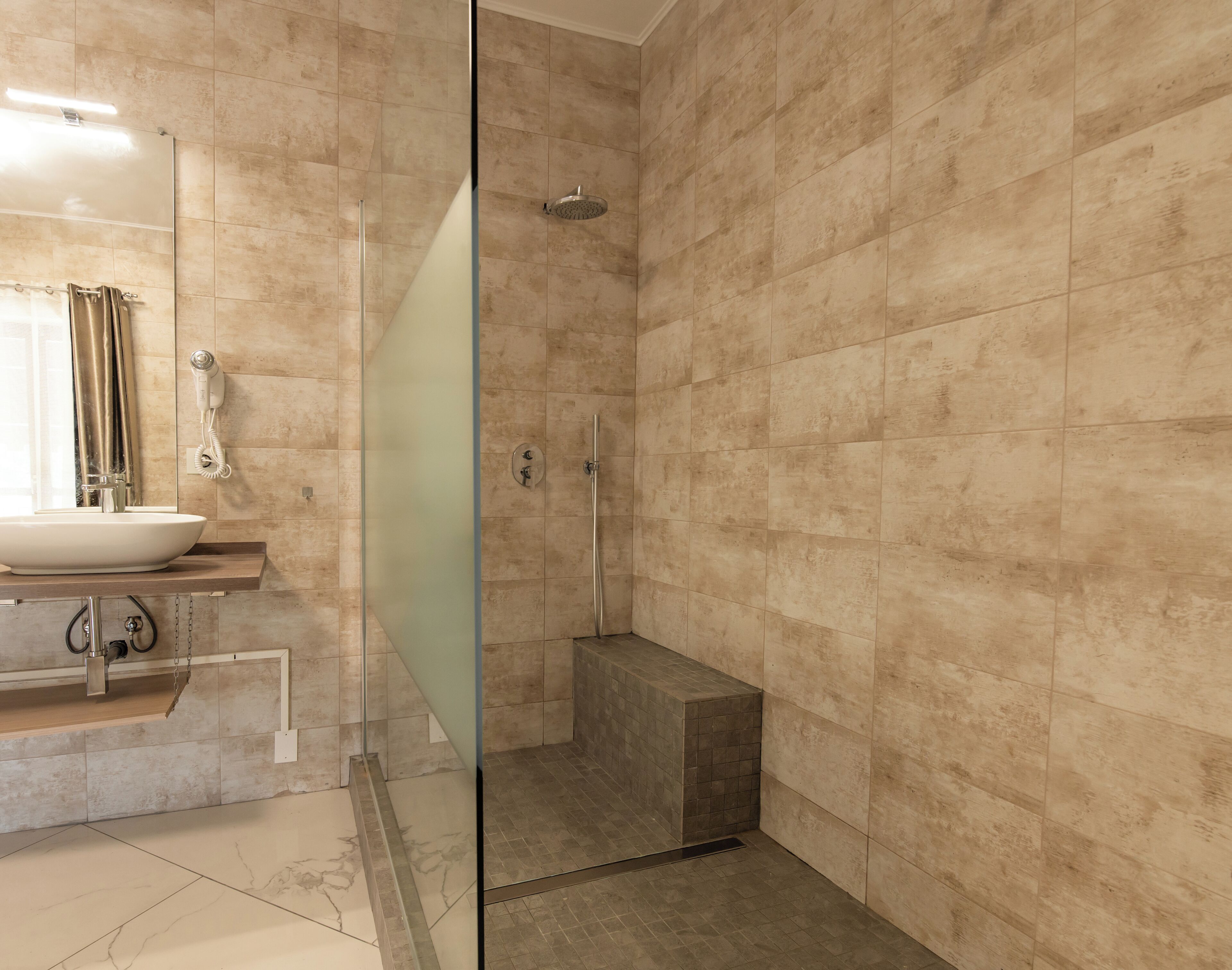 Un bany modern amb una cabina de dutxa de vidre, un lavabo amb mirall i una barra de tovalloles.