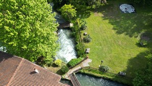An aerial view of a riverside property with a wooden bridge, a grassy lawn, and a tiled roof. - Villa Vitti's - Verona est  (San Martino Buon Albergo)